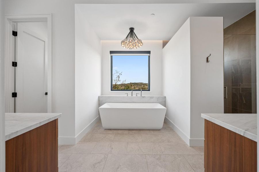 Bathroom featuring baseboards, a notable chandelier, a freestanding bath, and vanity Bathroom featuring baseboards, a notable chandelier, a freestanding bath, and vanity