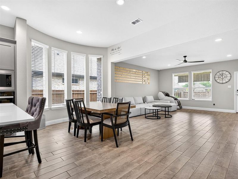 Open-concept living space featuring wood-finish flooring, recessed lighting, and multiple windows with blinds Open-concept living space featuring wood-finish flooring, recessed lighting, and multiple windows with blinds