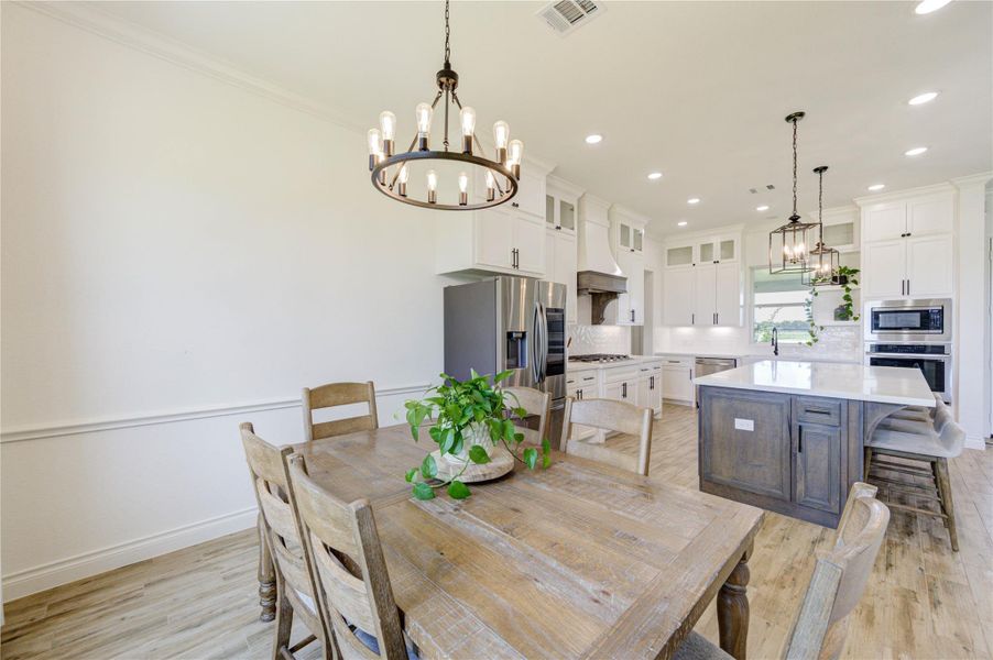 Bright dining area with modern lighting and open flow to kitchen and living room