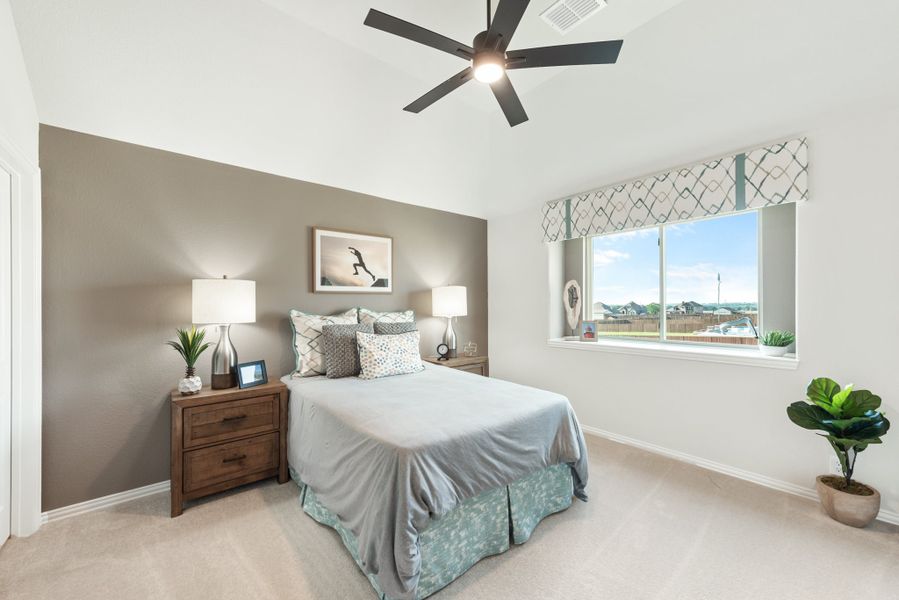 Bedroom with vaulted ceiling, ceiling fan, carpet floors, and large window with natural light