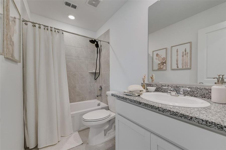 Bathroom featuring vanity, shower / bathtub combination with curtain, and tile patterned flooring Bathroom featuring vanity, shower / bathtub combination with curtain, and tile patterned flooring