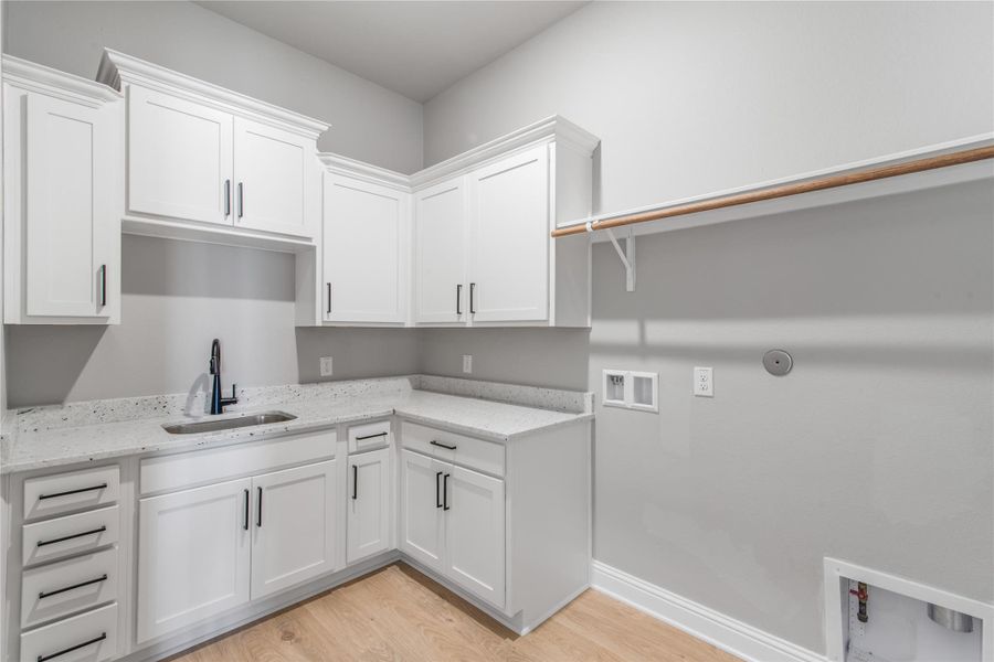 Expansive laundry room with abundant cabinetry, a sink, and space for extra appliances.