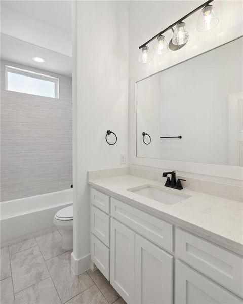 Full bathroom featuring tiled shower / bath combo, vanity, tile patterned floors, and toilet