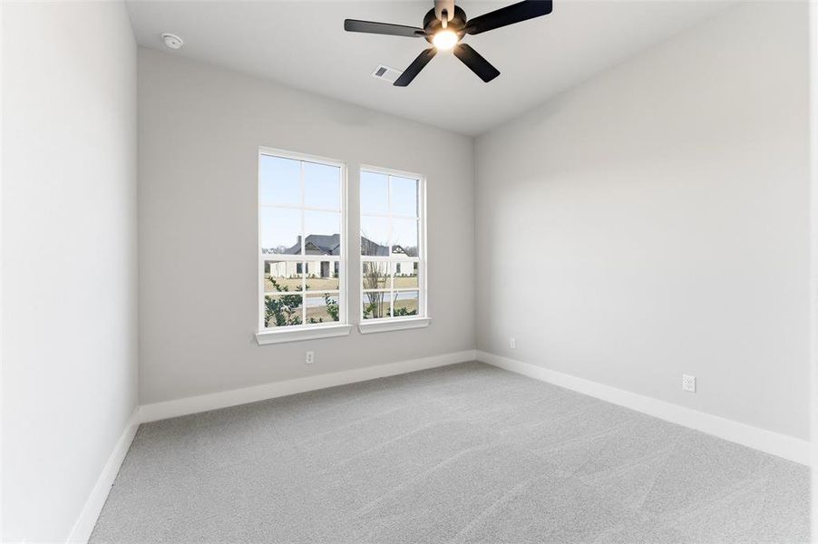 Empty room with light colored carpet and ceiling fan