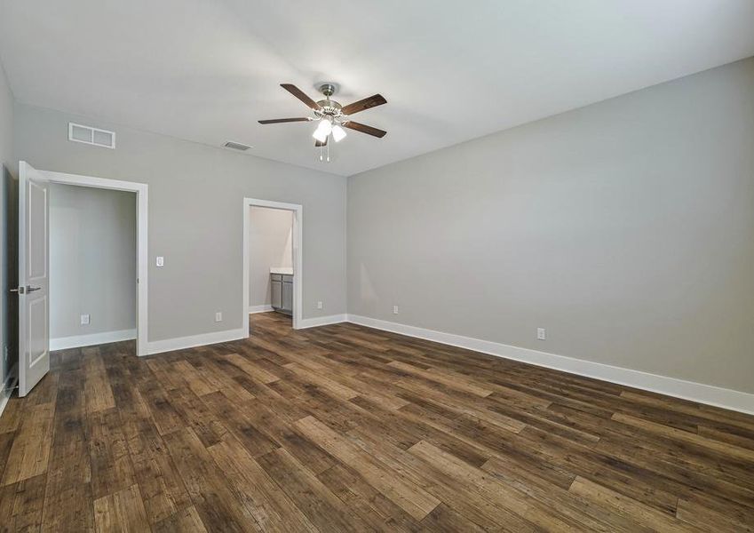 The master bedroom has beautiful hardwood flooring and a celling fan