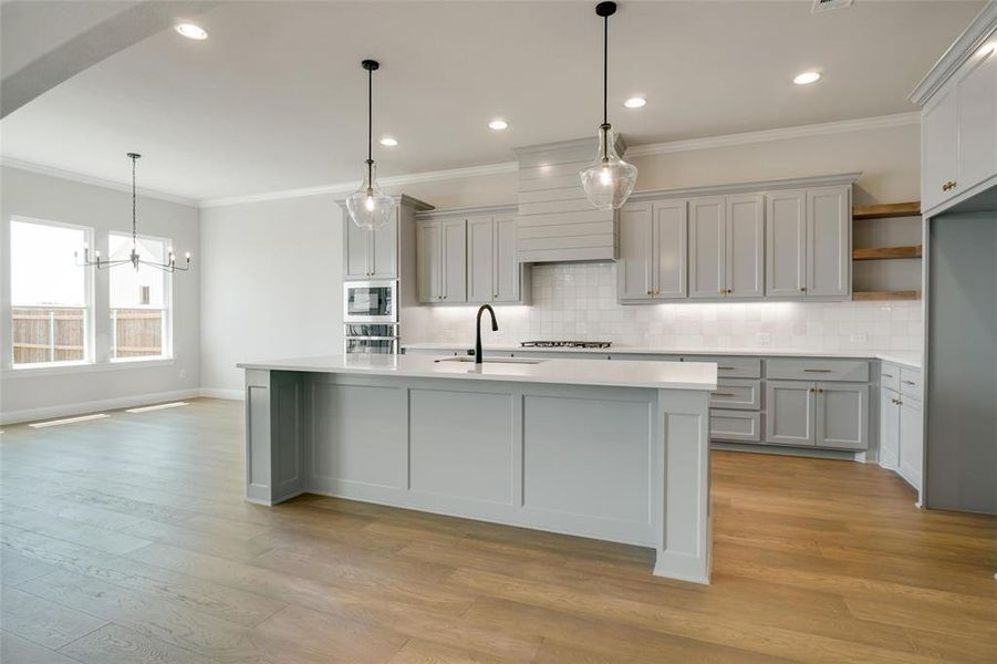 Kitchen featuring backsplash, appliances with stainless steel finishes, light wood-type flooring, and gray cabinetry