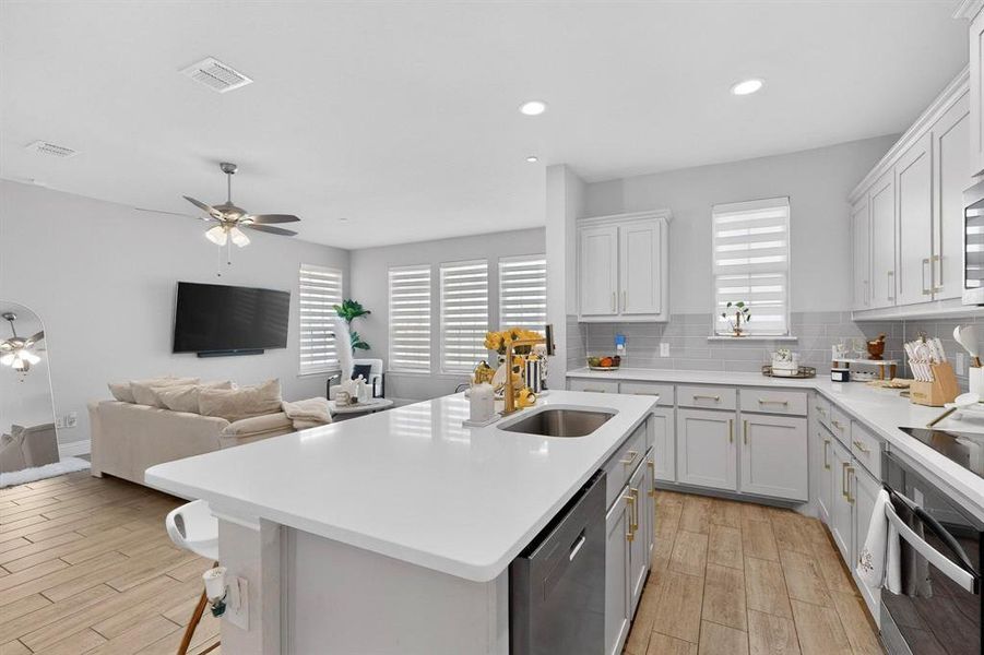 The kitchen features white cabinetry, light countertops, and a stainless steel sink with a gold-toned faucet