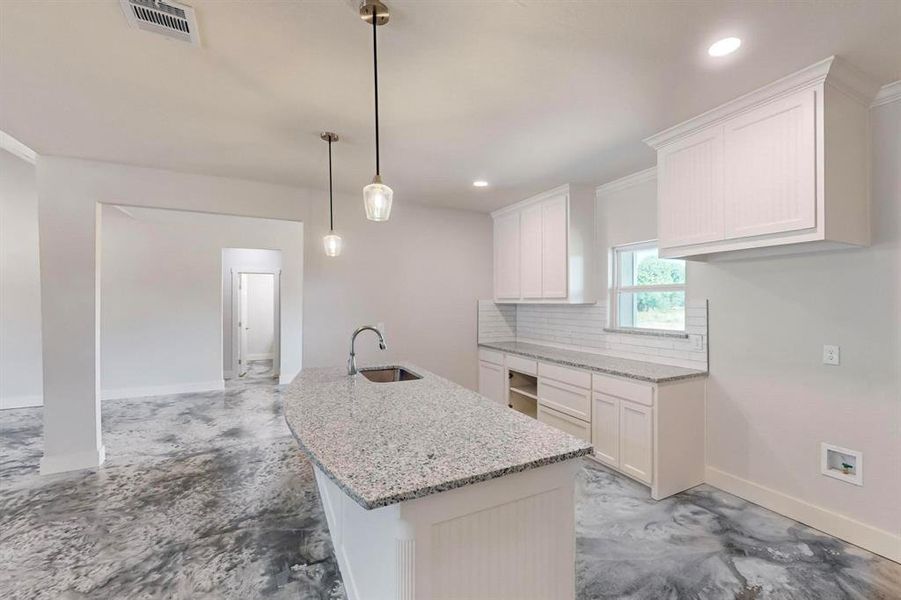 Kitchen featuring backsplash, white cabinetry, hanging light fixtures, and ornamental molding