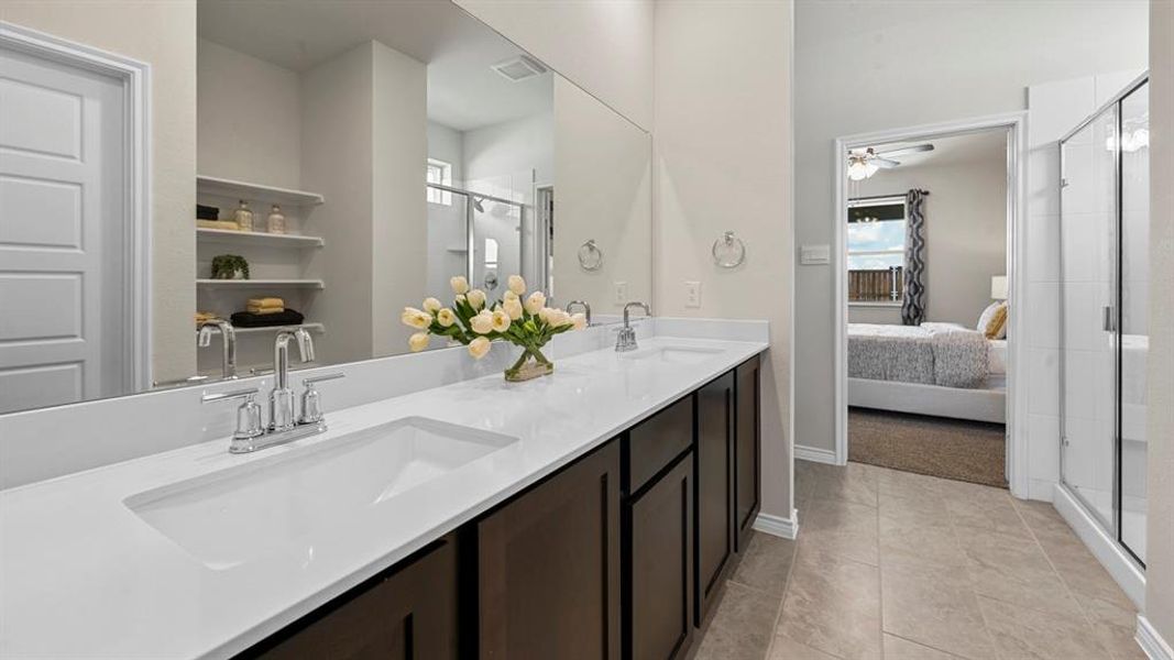 Ensuite bathroom featuring a stall shower, double vanity, ceiling fan, and light tile patterned flooring Ensuite bathroom featuring a stall shower, double vanity, ceiling fan, and light tile patterned flooring