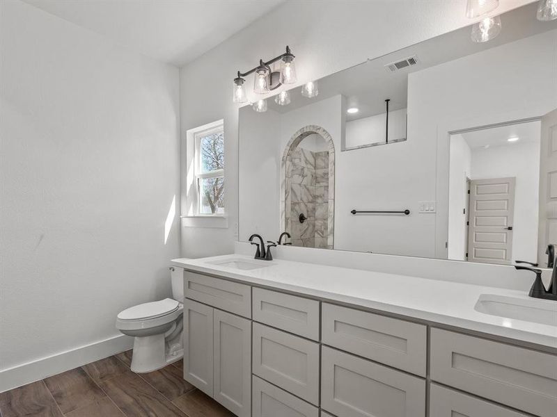 Bathroom with a sink, visible vents, toilet, and wood finished floors