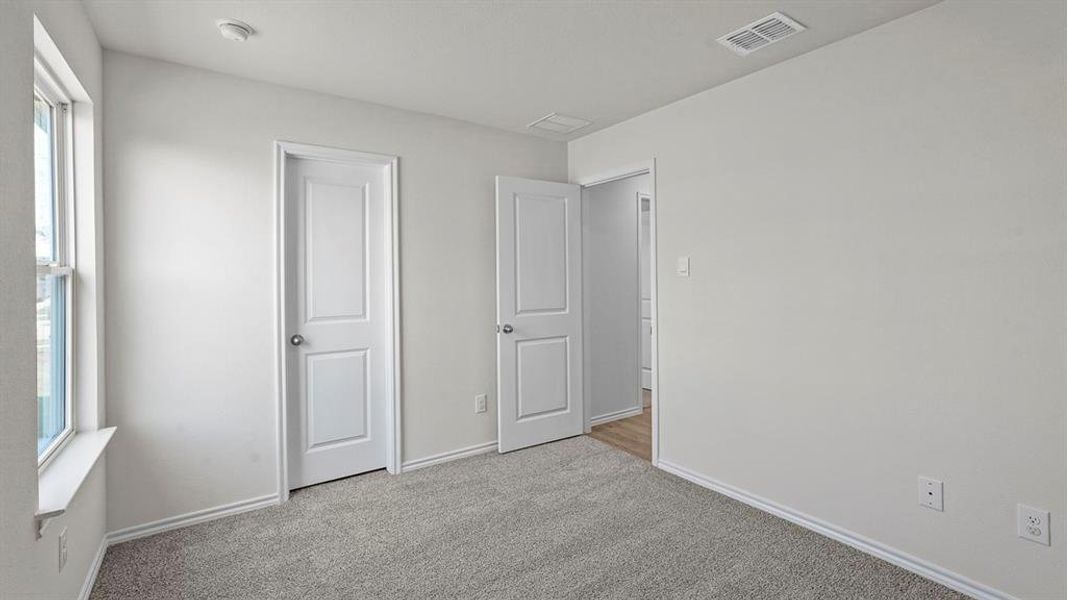Light gray carpeted room with white walls, baseboards, and window trim