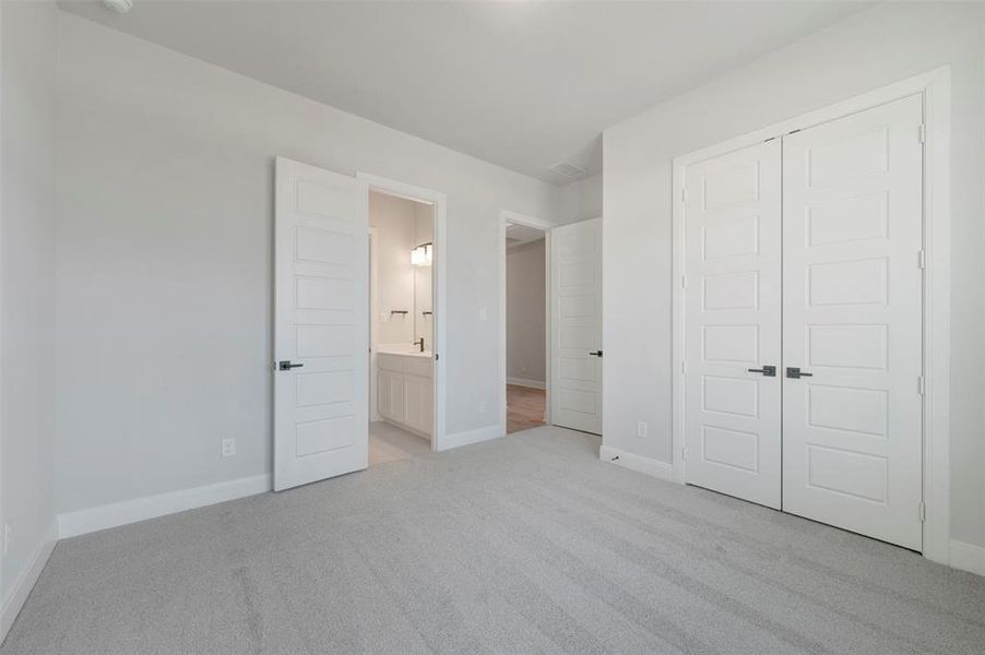 Unfurnished bedroom featuring light carpet, a closet, and connected bathroom
