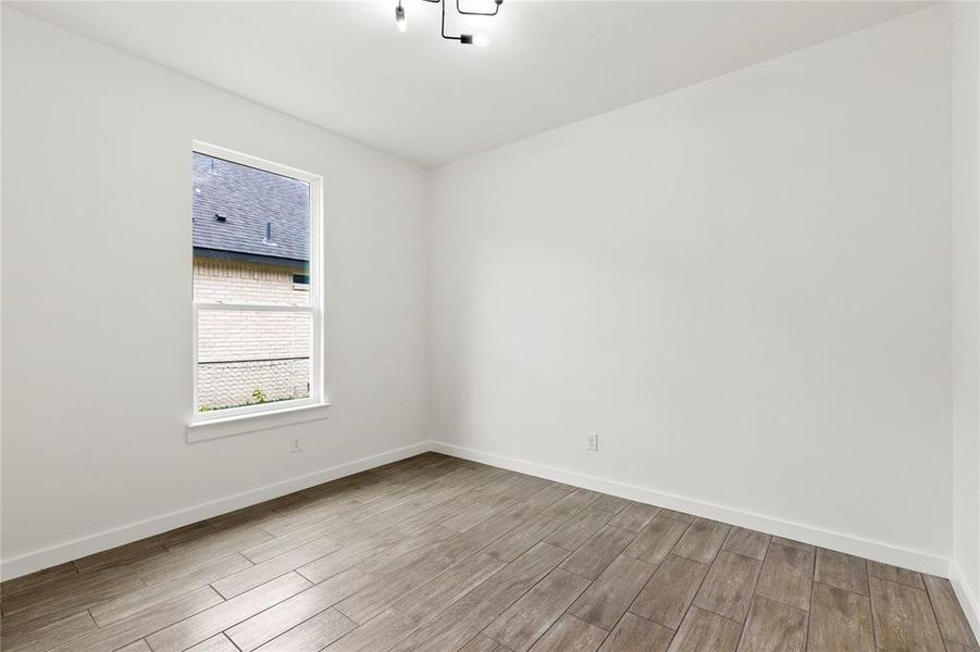 Room featuring wood-look tile flooring, white baseboards, a single window, and a modern ceiling light fixture