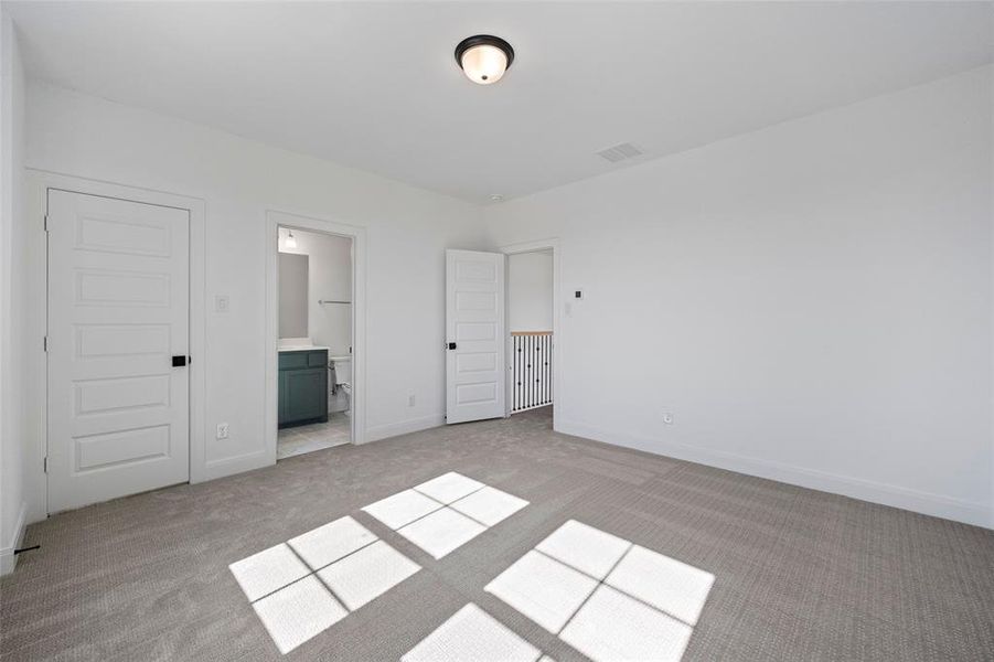 Unfurnished bedroom with a closet, light colored carpet, and ensuite bath