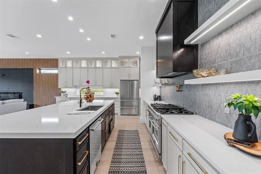 Kitchen featuring high end appliances, glass insert cabinets, decorative backsplash, white cabinets, and light stone counters