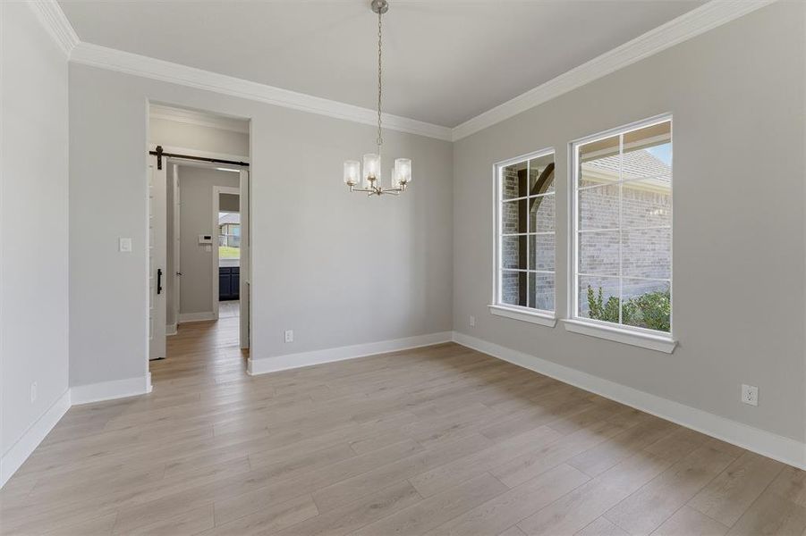 Bright interior space featuring light wood-finish flooring, a modern chandelier, and two large windows with grid accents