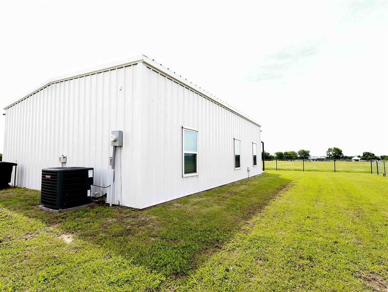 White corrugated metal building featuring multiple windows and an exterior HVAC unit