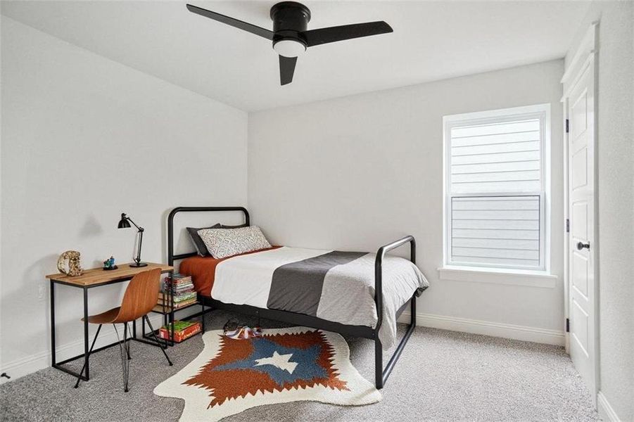 Carpeted bedroom with a ceiling fan and baseboards