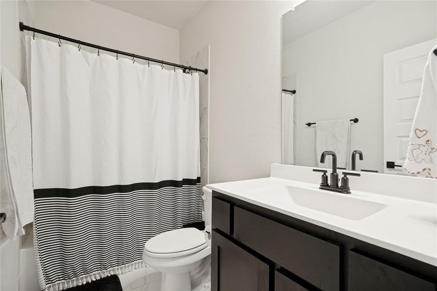 Bathroom featuring a dark wood vanity with a white countertop, an integrated rectangular sink, and a black-finish faucet