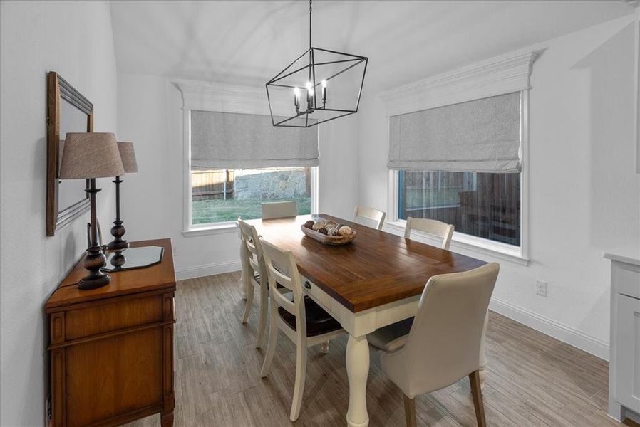 Dining room with an inviting chandelier, baseboards, and light wood-type flooring