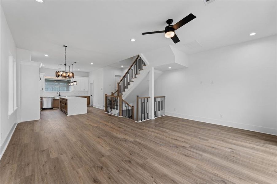 This home features an open-concept living area with sleek hardwood floors, a modern kitchen with a central island and stylish lighting, and a contemporary staircase leading to the upper floor. The space is bright and inviting, ideal for entertaining and family living.