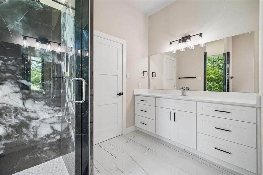Full bathroom with vanity and gorgeous, veined marble finish in shower.