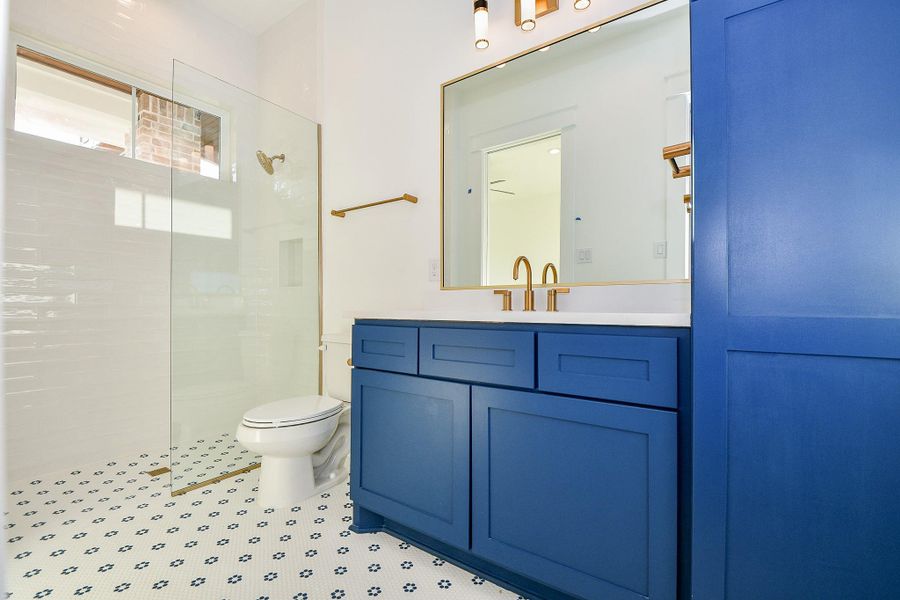 Sleek and stylish, the guest bath showcases a striking blue vanity with gold hardware, a modern walk-in shower with glass enclosure, and charming mosaic tile flooring that ties it all together. Sleek and stylish, the guest bath showcases a striking blue vanity with gold hardware, a modern walk-in shower with glass enclosure, and charming mosaic tile flooring that ties it all together.