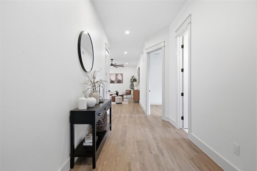 A lengthy hallway with light wood flooring leads to an open living area, offering a sense of depth. A lengthy hallway with light wood flooring leads to an open living area, offering a sense of depth.
