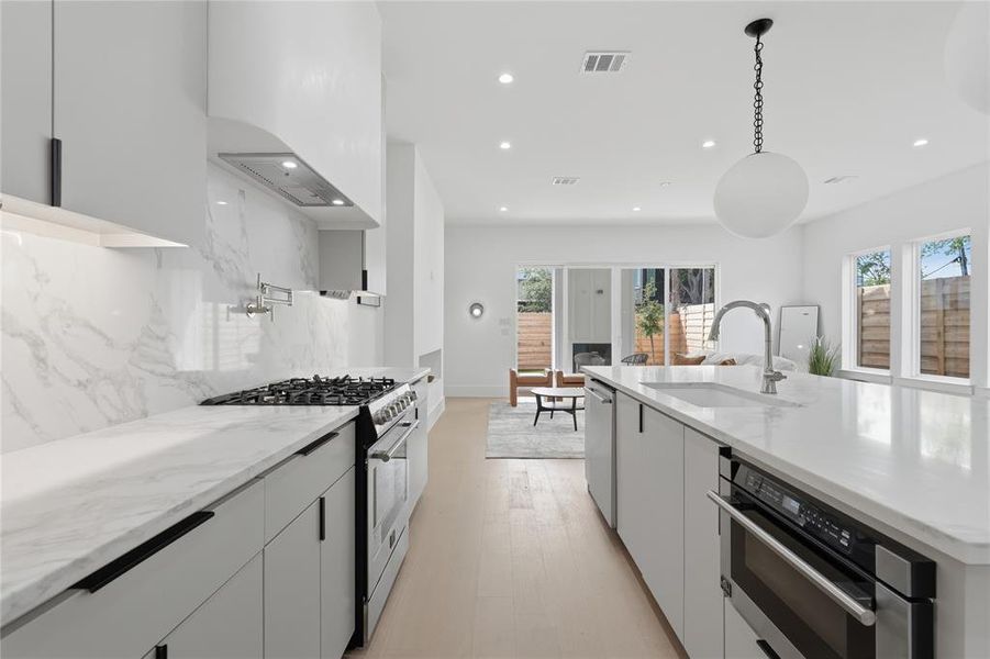 Open-concept kitchen featuring an expansive island with an undermount sink, built-in microwave, and integrated dishwasher