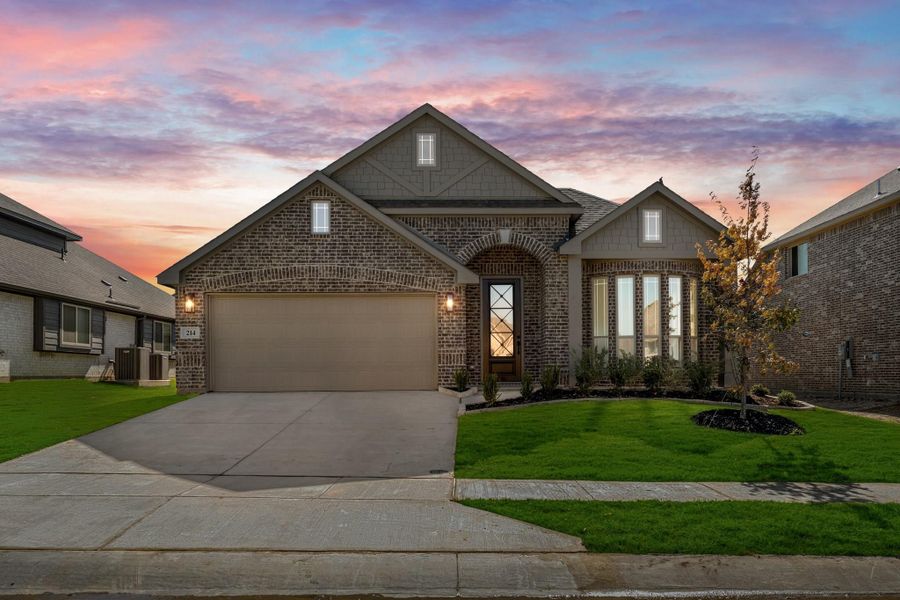 Single-story brick home with two-car garage, arched entry, and manicured front lawn at dusk Single-story brick home with two-car garage, arched entry, and manicured front lawn at dusk