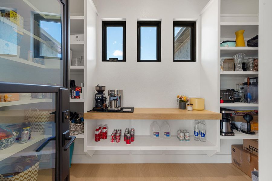 Custom built-in shelving and ample counter space highlight this highly functional walk-in pantry.