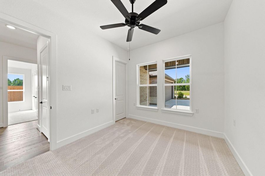 Comfortable secondary bedroom with a ceiling fan, natural light, and easy access to the home’s additional living spaces.