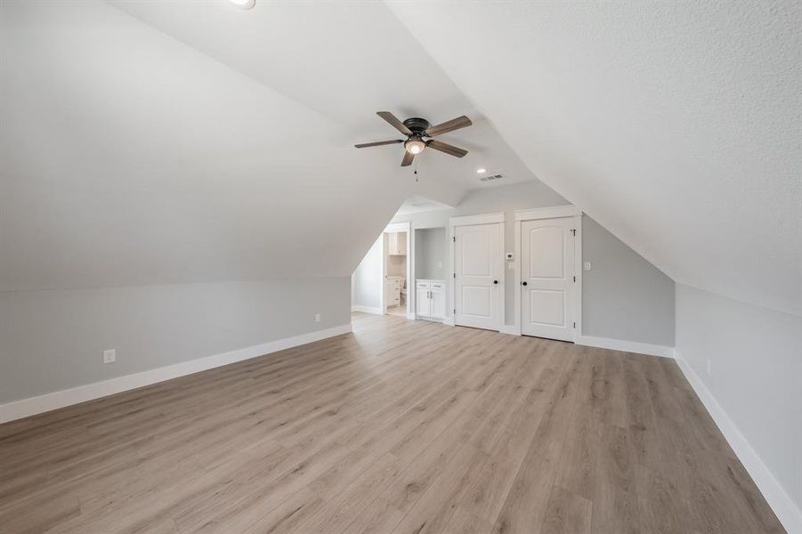 Bonus room with light hardwood / wood-style flooring, vaulted ceiling, and ceiling fan