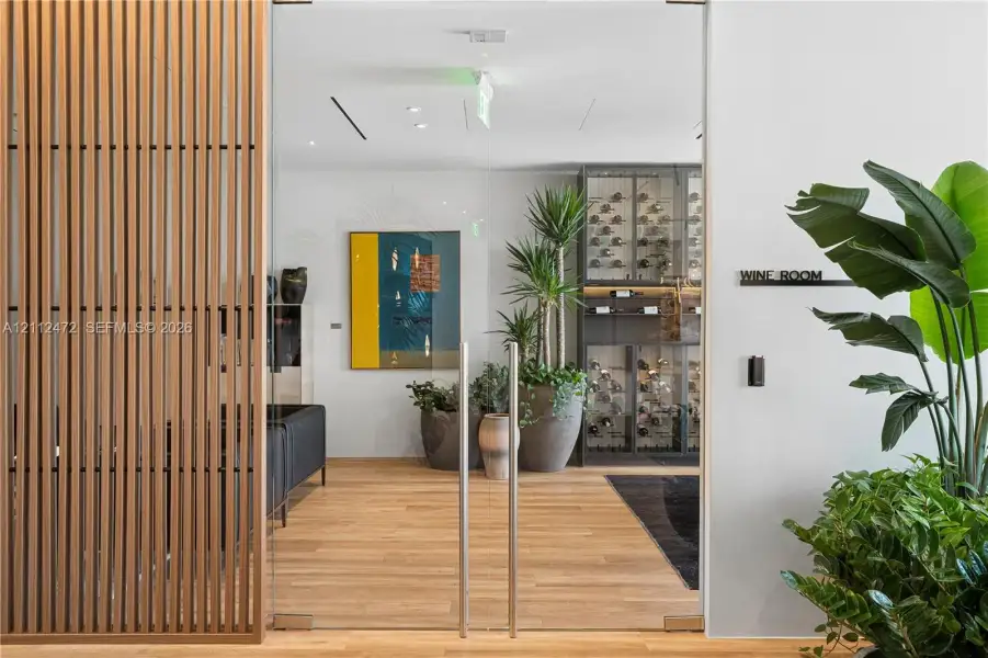 Wine room featuring frameless glass double doors, vertical wood-slat screening, and built-in metal display racking with integrated shelving