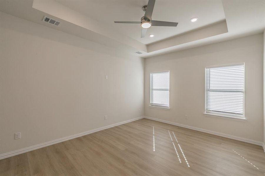 Spare room featuring ceiling fan, a raised ceiling, and light hardwood / wood-style flooring