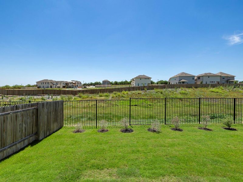 Expansive backyard featuring a lush lawn, privacy fencing, and a wrought iron style fence