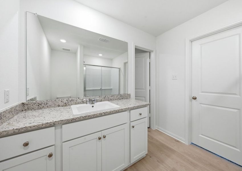 Primary bathroom featuring a double vanity with granite countertop and a large mirror. Primary bathroom featuring a double vanity with granite countertop and a large mirror.
