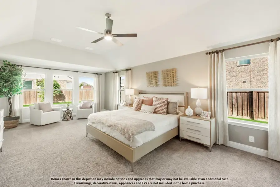 Spacious master bedroom with vaulted ceiling, ceiling fan, carpet flooring, and large windows with natural light.