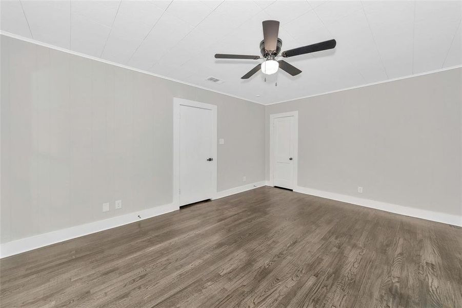 Empty room with a ceiling fan, wood finished floors, and crown molding Empty room with a ceiling fan, wood finished floors, and crown molding