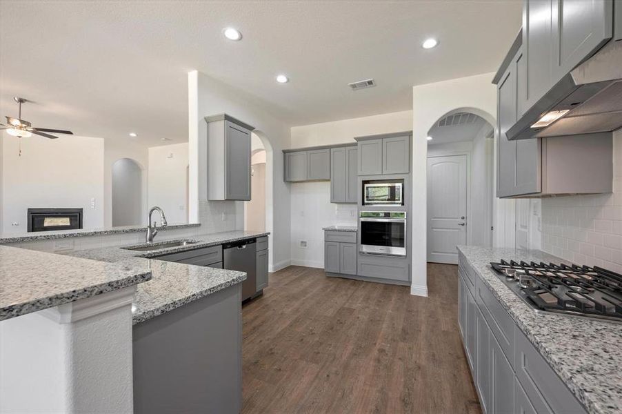 Kitchen featuring sink, stainless steel appliances, gray cabinets, range hood, and dark hardwood / wood-style floors