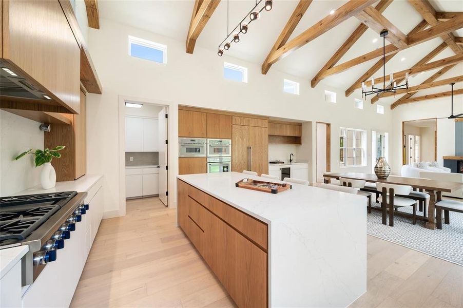 Kitchen featuring light hardwood / wood-style floors, range, and high vaulted ceiling