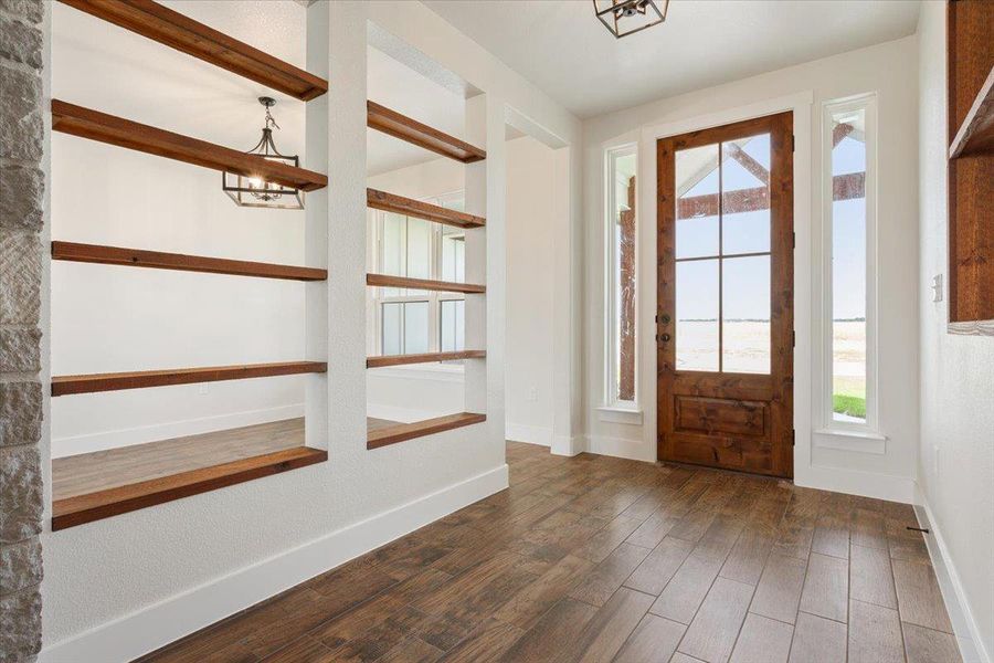 A welcoming entry features rich wood flooring and an inviting glass-paned front door, framed by tall sidelights.