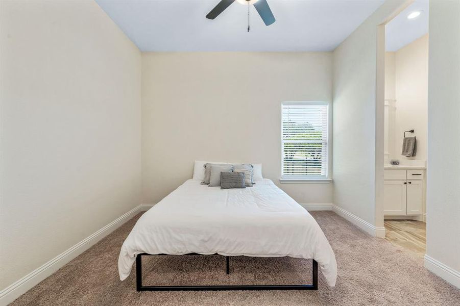Bedroom featuring light colored carpet, ensuite bathroom, and a ceiling fan Bedroom featuring light colored carpet, ensuite bathroom, and a ceiling fan