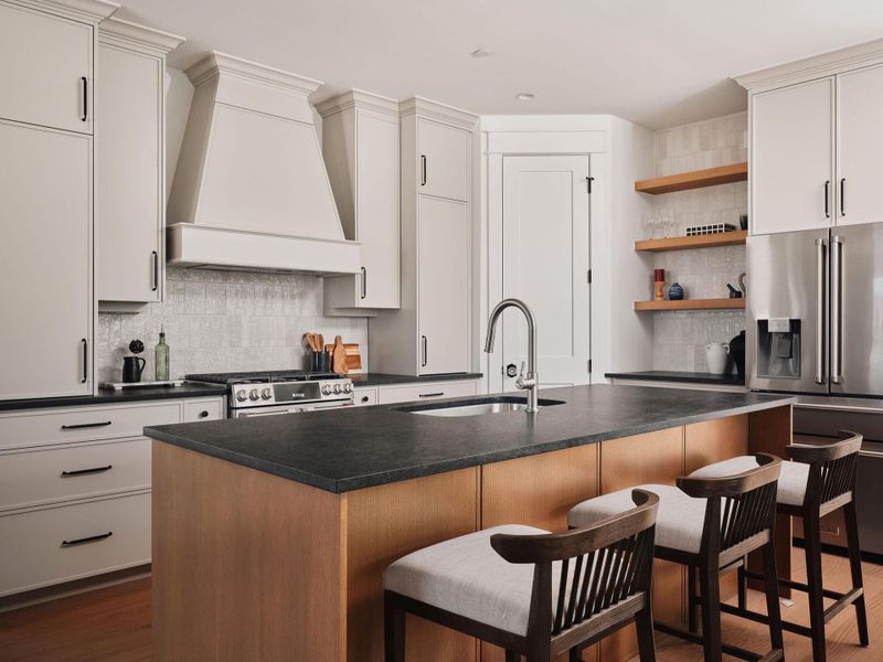 Kitchen with stainless steel appliances, a kitchen island with sink, dark wood-style flooring, and a kitchen bar