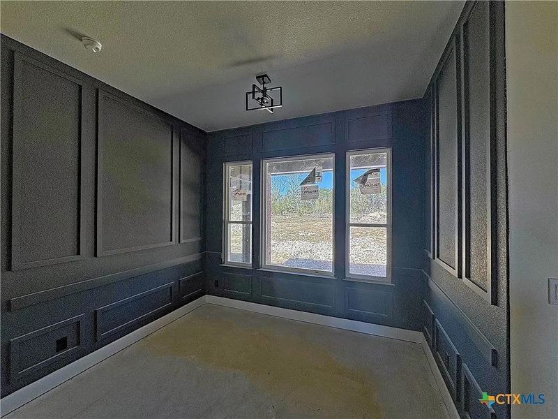 Spare room featuring a textured ceiling, concrete flooring, and a decorative wall