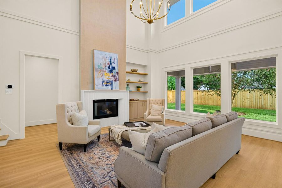 The dramatic two-story living room features impressive 20-foot ceilings, expansive windows, a designer fireplace, and custom built-ins that create a warm yet sophisticated gathering space. The dramatic two-story living room features impressive 20-foot ceilings, expansive windows, a designer fireplace, and custom built-ins that create a warm yet sophisticated gathering space.