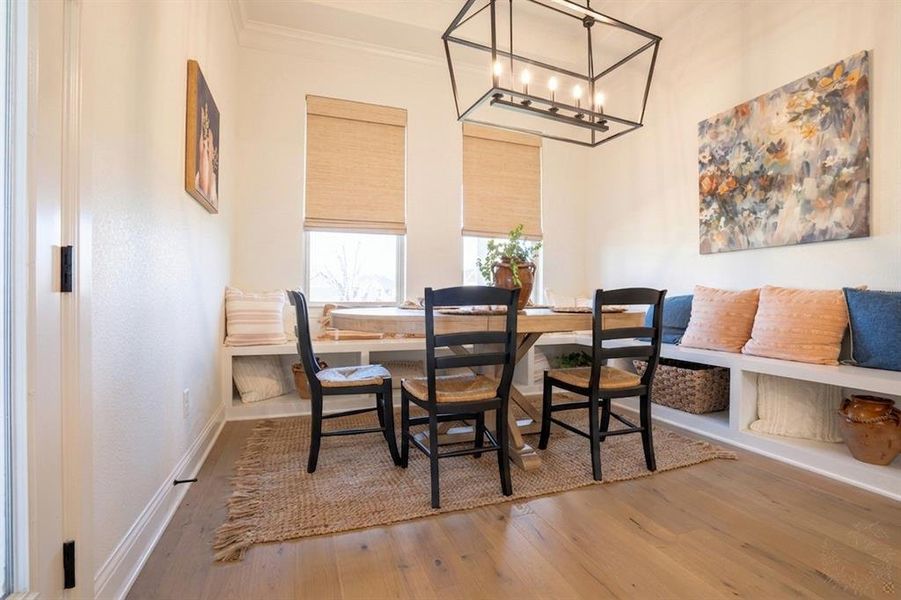 Dining area with light wood-style floors, ornamental molding, and suspended lighting