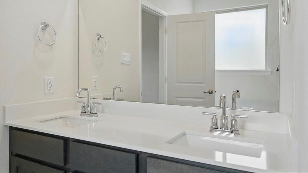 Dual vanity featuring a white countertop, undermount sinks, chrome faucets, and dark cabinetry