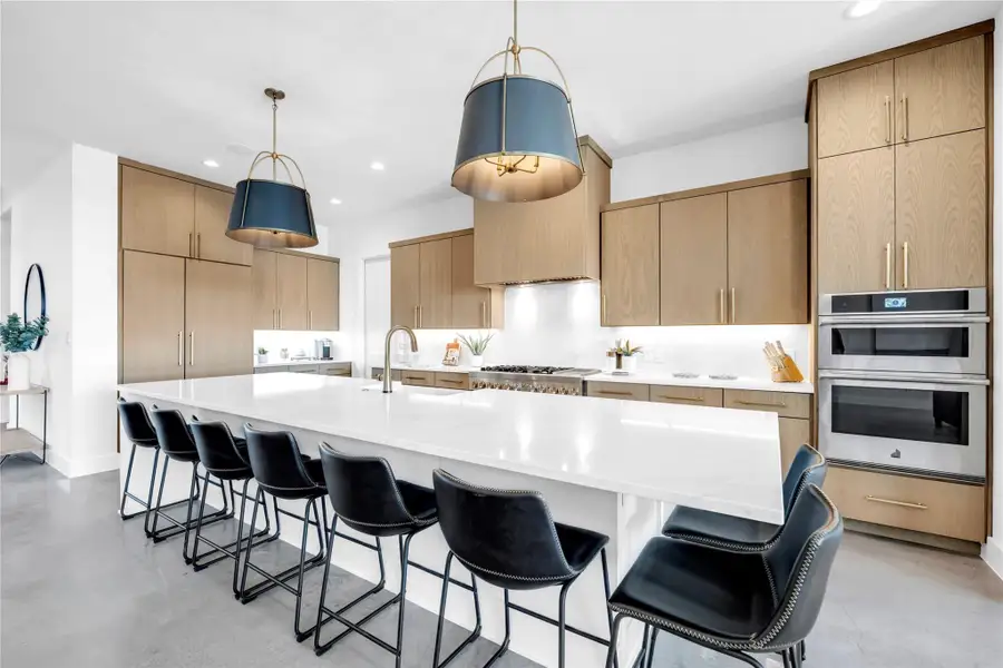 Sleek flat-panel wood cabinetry and a massive quartz island define this contemporary culinary space.