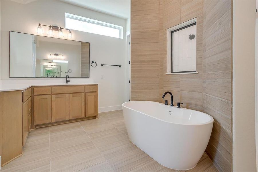 Bathroom featuring tile patterned floors, tile walls, a tub to relax in, and vanity